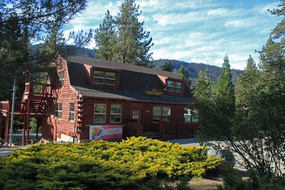 Red village building with hedges and pine trees in Pine Mountain Club