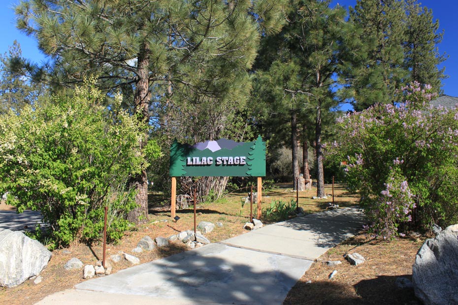 Pine Mountain Club village center sign at the entrance to a shaded walkway
