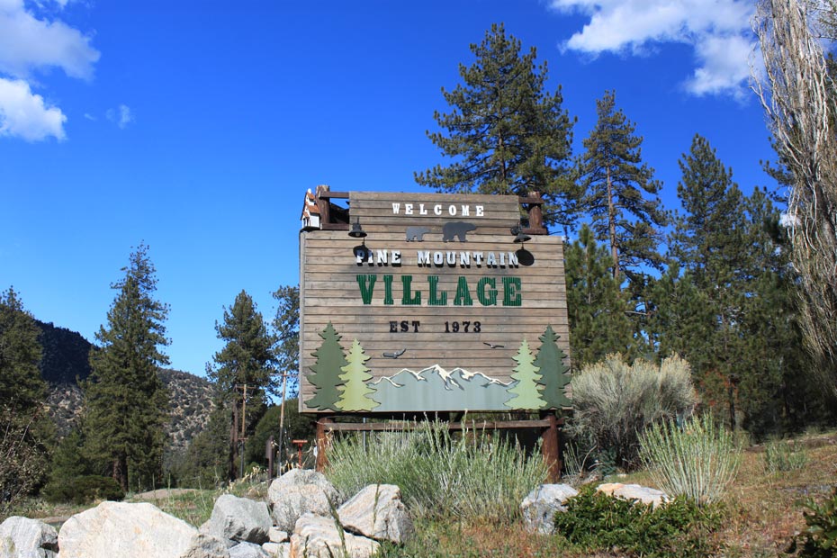 Pine Mountain Club village entrance sign surrounded by boulders and pine trees